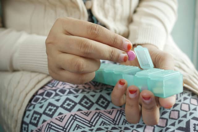 Stock image: Woman taking medicine from a pill box