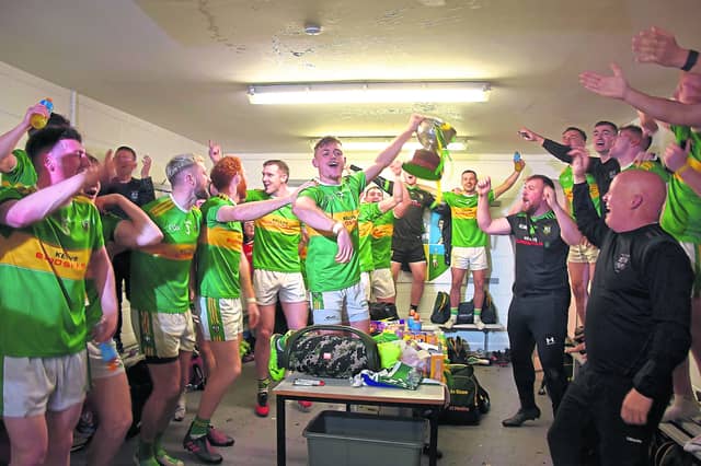 A delighted Eunan Mulholland raises the trophy to his team mates in the dressing room. Pic by Mary K Burke