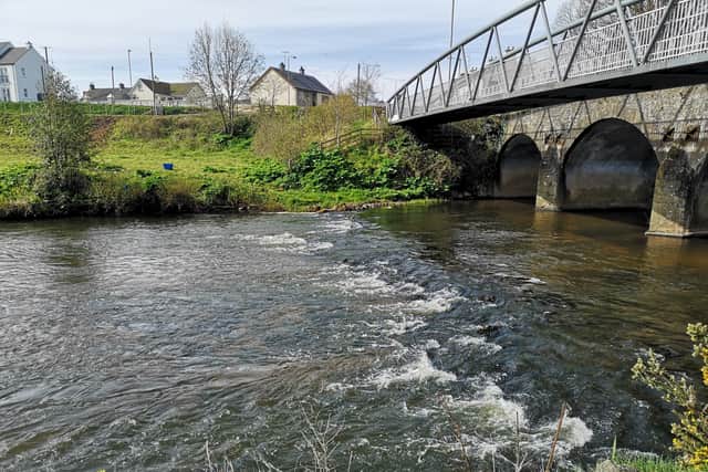Water plateaus underneath the footbridge before cascading downstream towards Lough Neagh through rocks hidden beneath its surface.