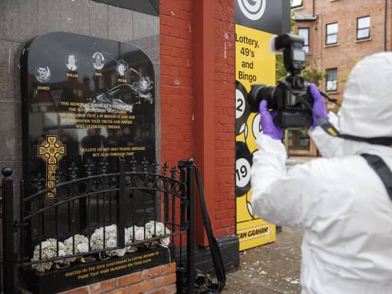 A police investigator photographs a vandalised memorial in Belfast