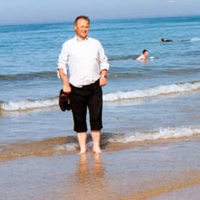 Fr Paddy O'Kane paddling in the water at Culdaff Beach. A new book is being written about the beloved late priest, with people being asked to share their memories of him.