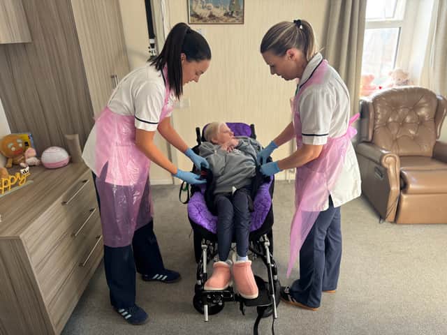 Caoimhe and Samantha help Elizabeth into her bespoke moulded wheelchair.