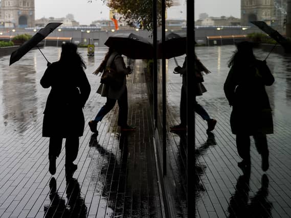 People shelter under umbrellas from the rain near Tower Bridge, central London