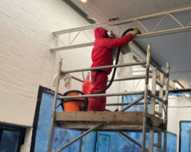 Removing asbestos insulating board from a school sports hall