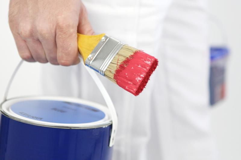Pot de peinture et pinceau dans la main d'un homme