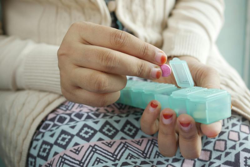 Woman taking medicine from a pill box