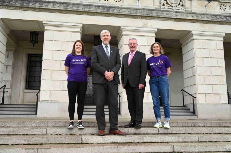 Finance Minister John O’Dowd & Health Minister Mike Nesbitt with Sands reps Rachel McGonigle & Kelly Barnes wearing their Baby Loss Awareness Week ribbon badges in support of the baby loss community.